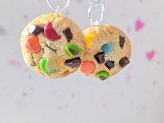 two cookies with m & m's on them hanging from silver earwires