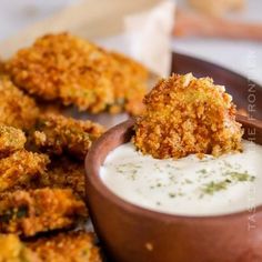 some fried food is in a bowl on a plate next to dipping sauce and breadsticks