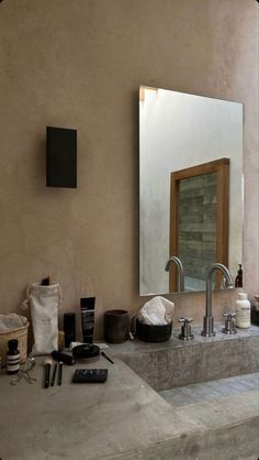 a bathroom sink sitting under a large mirror next to a wall mounted faucet