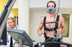 a man wearing a gas mask while standing next to a woman on a treadmill