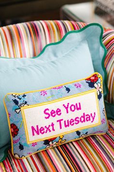 a pillow that says see you next tuesday on the back of a chair with striped cushions