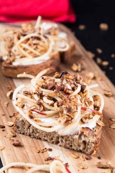 two slices of bread topped with toppings on top of a wooden cutting board next to another piece of bread