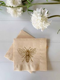 a napkin with a bee on it next to some flowers