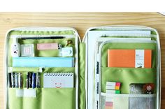 an open green case filled with lots of office supplies on top of a wooden table