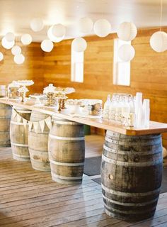 wine barrels are lined up on the floor with bottles and glasses in front of them