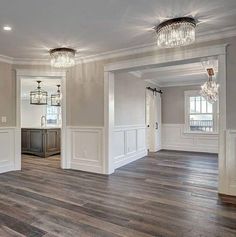 an empty living room with wood floors and chandeliers