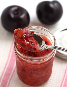 a spoon with some food in it on a table next to plums and cherries