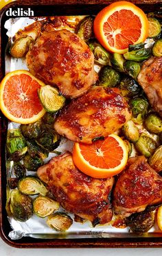 chicken, brussel sprouts and oranges on a baking sheet