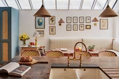 an open kitchen and living room with pictures on the wall above the sink, in front of a large window