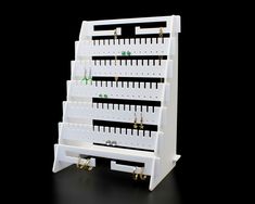 a white display rack with earrings and earring hooks on it's sides, against a black background