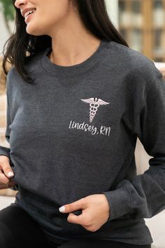 Personalized nurse sweatshirts keep you warm in the coolest of work places. This makes the perfect gift for new nurses, RN or LPN graduation, or nurse appreciation week, and includes the credentials they worked so hard for. Features soft fleece lining and banded hem.  ✨PREVIEW NAME OR TEXT✨ https://app.fontvisual.com/showcases/78b7b8b1-6911-4df2-8e8f-7c557d2d189c ♥ SIZING AND ITEM DETAILS ♥ ▹ Listing photos contain sizing, details, and color options. ▹ Design is Embroidered. ▹ Shirts are UNISEX Lpn Graduation, Nursing Sweatshirt, Medical Scrubs Outfit, Cna Nurse, Nurse Appreciation Week, Gifts For Nurses, Or Nurse, Scrubs Outfit, Embroidered Shirts