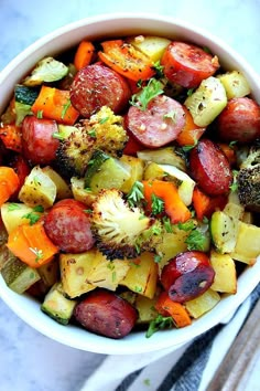 a white bowl filled with potatoes, carrots and broccoli on top of a table