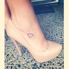 a woman's foot with a small heart tattoo on her left side shoe heel