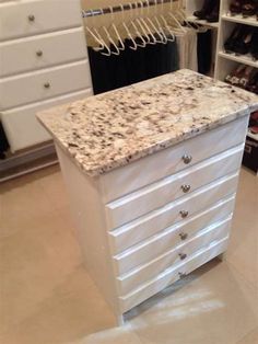 a white dresser with marble top in a closet