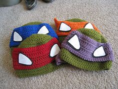 three crocheted teenage mutant hats laying on the floor next to a pair of shoes