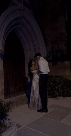 a man and woman standing next to each other in front of a building at night