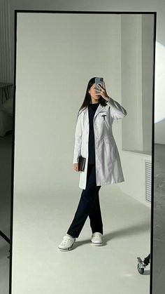 a woman taking a photo with her cell phone in front of a white background,