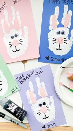 some bunny handprints are sitting on a table next to paint and crayons