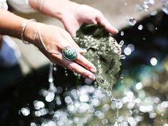 a woman's hand reaching for a leaf with water splashing on it and bubbles in the air