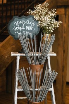 a vase filled with white flowers sitting on top of a wooden chair next to a chalkboard