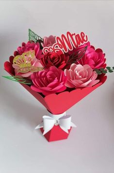 a bouquet of paper flowers in a red box with the word love spelled on it