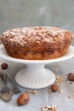 a cake sitting on top of a white plate covered in nuts and powdered sugar