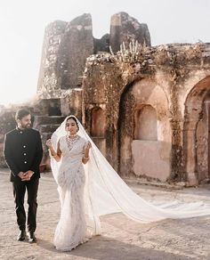 a bride and groom walking in front of an old building with stone walls, archways and arches