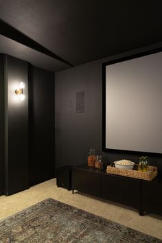 an empty room with a large screen on the wall and a rug in front of it