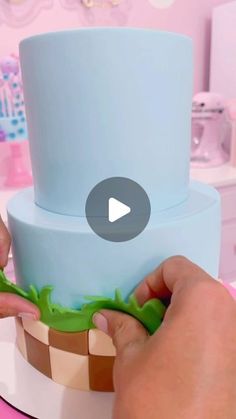 a person is decorating a cake with fondant and icing on a pink table