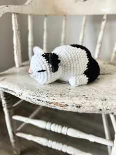 a small black and white cat sitting on top of a wooden chair