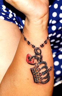 a woman's arm with a tattoo on it that has a crown and heart