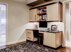 a home office with an area rug on the floor and wooden cabinets in front of it