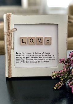 a wooden scrabble with the word love spelled in it next to some flowers