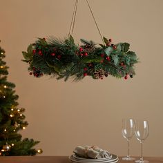 a christmas wreath hanging over a table with two wine glasses and silverware on it