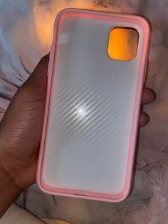 a person holding a pink and white cell phone case in their left hand, with an orange light shining on it