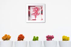 five white bowls with different colored flowers in them and a framed artwork on the wall