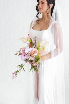 A Bride Looking To The Side With A Soft Smile Holding Her Bouquet.