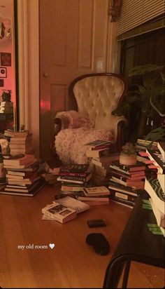 a pile of books sitting on top of a hard wood floor next to a chair