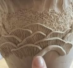 a person is holding up a clay vase that looks like it has been carved into the surface