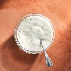 a bowl of yogurt with a spoon in it on a brown table top