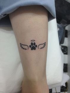 a dog paw with angel wings tattoo on the leg