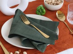 a white plate topped with green napkins next to silverware and other food items