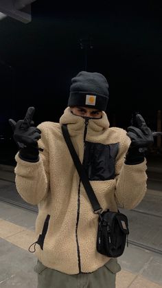 a person wearing a jacket and hat holding up two fingers