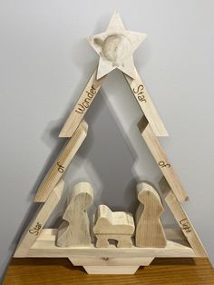 a wooden christmas tree with two nativity figures in it and a star on top