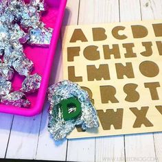 two trays filled with foil and letters next to each other on top of a table