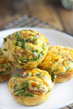 three muffins on a plate with spinach and cheese in the middle, sitting on a wire rack