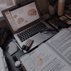 an open laptop computer sitting on top of a desk next to papers and other items