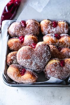 powdered sugar covered donuts in a metal pan with cherries on top, ready to be eaten