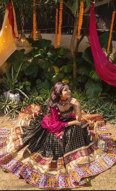 a woman sitting on top of a colorful blanket