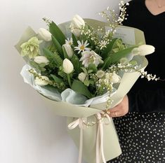 a woman holding a bouquet of white flowers